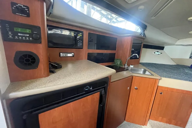 Slide: The Image of 2006 Bayliner 305 interior with kitchenette, featuring microwave, sink, and cozy sleeping area. - 18