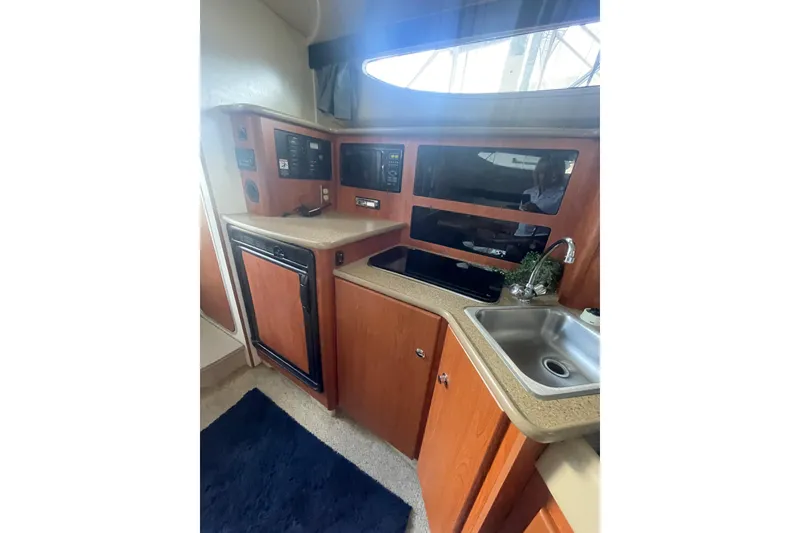 Slide: The Image of Interior of 2006 Bayliner 305 boat kitchen with sink, microwave, and fridge. - 19