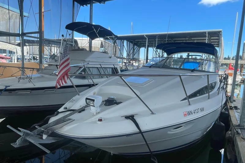 Slide: The Image of 2006 Bayliner 305 boat docked in marina, featuring sleek design and American flag. - 2