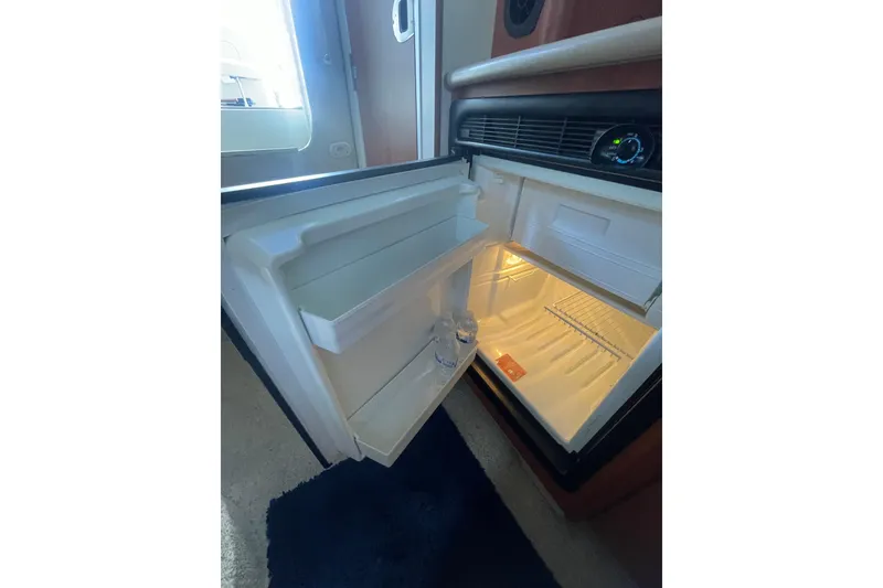 Slide: The Image of Open refrigerator inside 2006 Bayliner 305 boat cabin, showing interior shelves and door storage. - 20