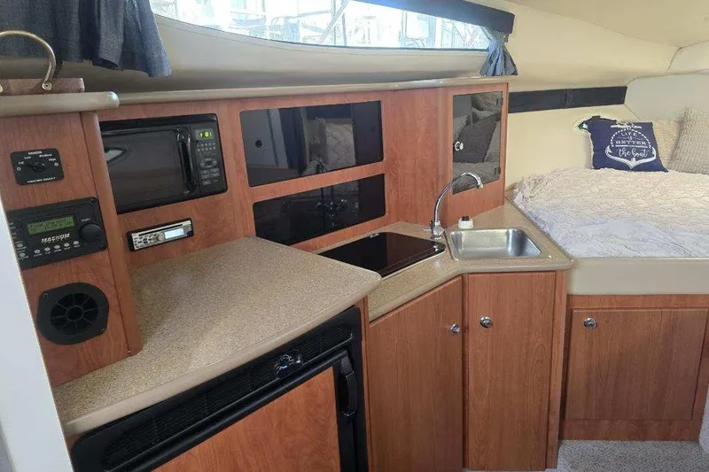 Slide: The Image of Interior of a 2006 Bayliner 305 boat featuring a compact kitchen and cozy sleeping area. - 24