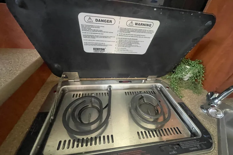 Slide: The Image of 2006 Bayliner 305 stove with safety warnings, featuring dual burners and countertop setting. - 26