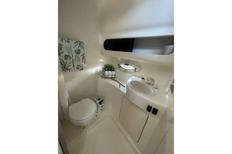 Slide: The Image of Compact bathroom in a 2006 Bayliner 305 boat, featuring a toilet, sink, and window. - 28