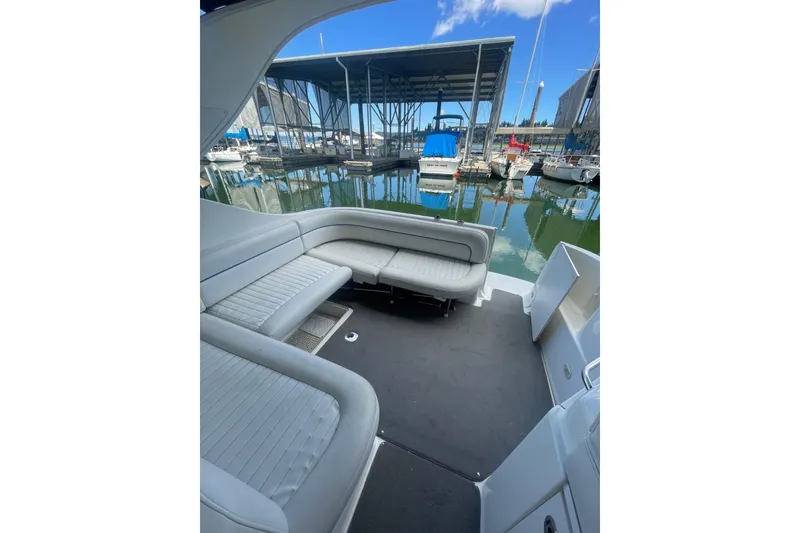 Slide: The Image of 2006 Bayliner 305 boat interior with seating, docked at a marina under clear blue skies. - 3