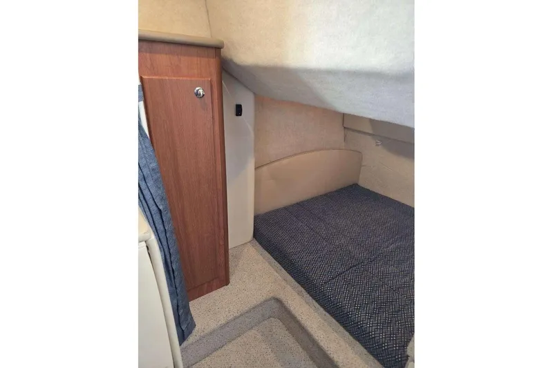 Slide: The Image of 2006 Bayliner 305 cabin interior with cozy sleeping area and wooden cabinet. - 30