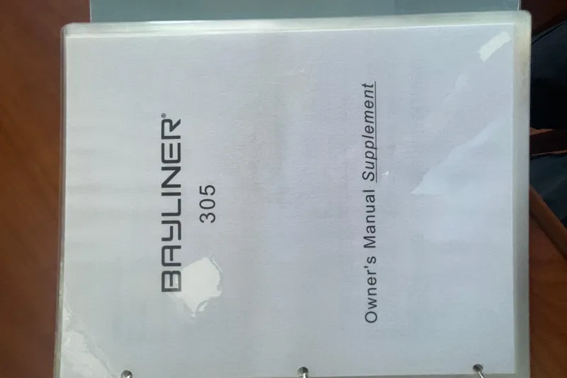 Slide: The Image of Bayliner 305 2006 owner's manual supplement cover on a wooden surface. - 37