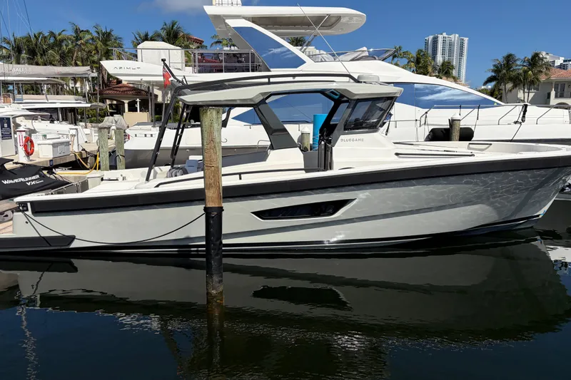 Slide: The Image of 2021 Bluegame BG 42 yacht docked at marina, surrounded by other boats and palm trees. - 1