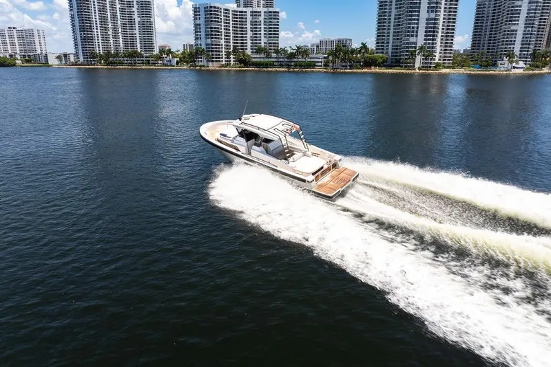 Slide: The Image of 2021 Bluegame BG 42 yacht cruising on water with city skyline backdrop. - 19