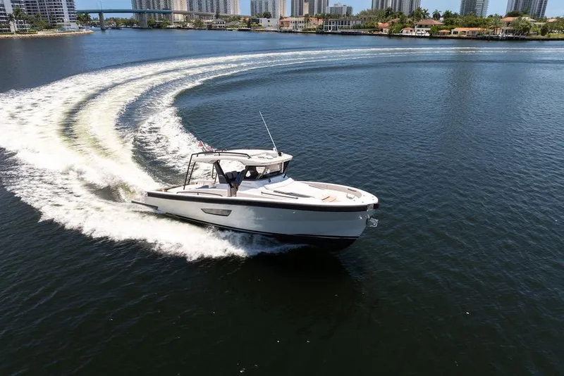 Slide: The Image of 2021 Bluegame BG 42 yacht cruising on a scenic waterway with city skyline backdrop. - 23
