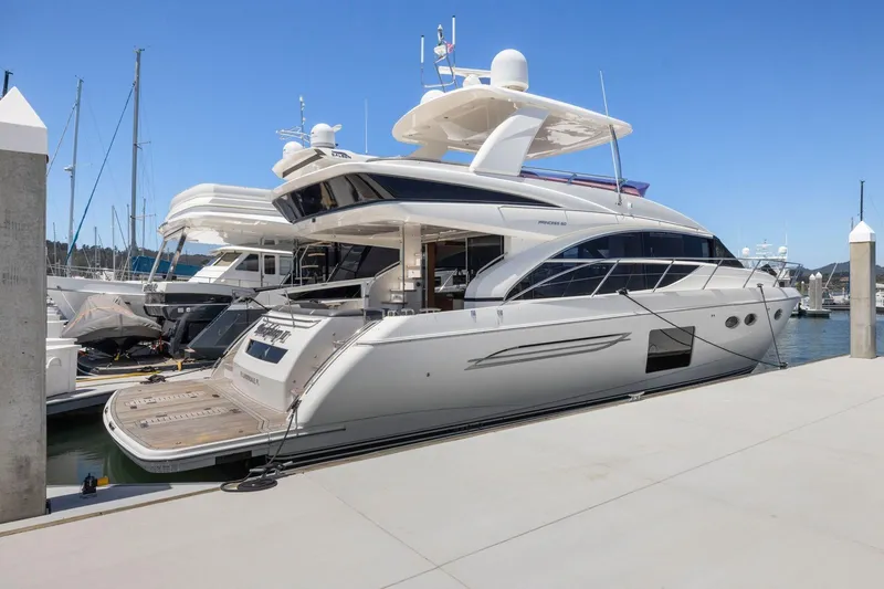 Slide: The Image of 2015 Princess 60 Flybridge Motor Yacht docked at marina under clear blue sky. - 2