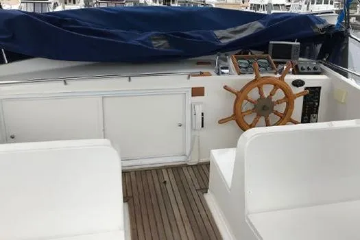 Slide: The Image of 1988 Grand Banks 46 Classic yacht helm with wooden wheel and covered dashboard. - 13