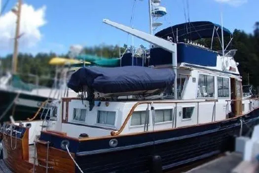 The Image of 1988 Grand Banks 46 Classic yacht docked, featuring a blue and white exterior with covered upper deck. - 2