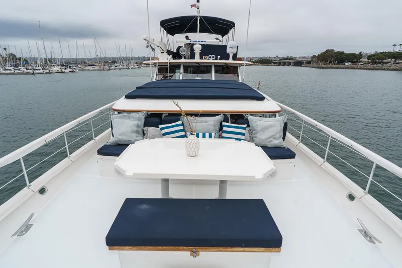 Slide: The Image of 1969 Burger Flush Deck yacht with elegant seating, cushions, and table on deck, docked in a marina. - 16
