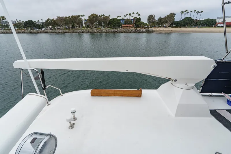 Slide: The Image of 1969 Burger Flush Deck yacht with davit arm, docked near a scenic shoreline. - 24
