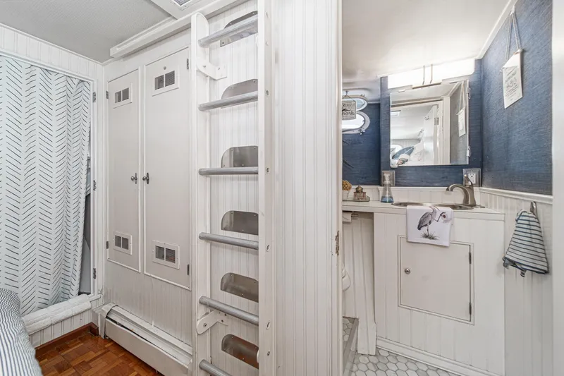 Slide: The Image of 1969 Burger Flush Deck yacht interior with white cabinetry, ladder, and compact bathroom. - 68