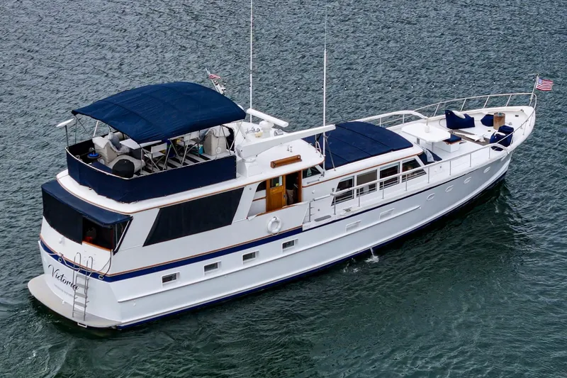Slide: The Image of 1969 Burger Flush Deck yacht cruising on water with blue canopy and sleek design. - 8