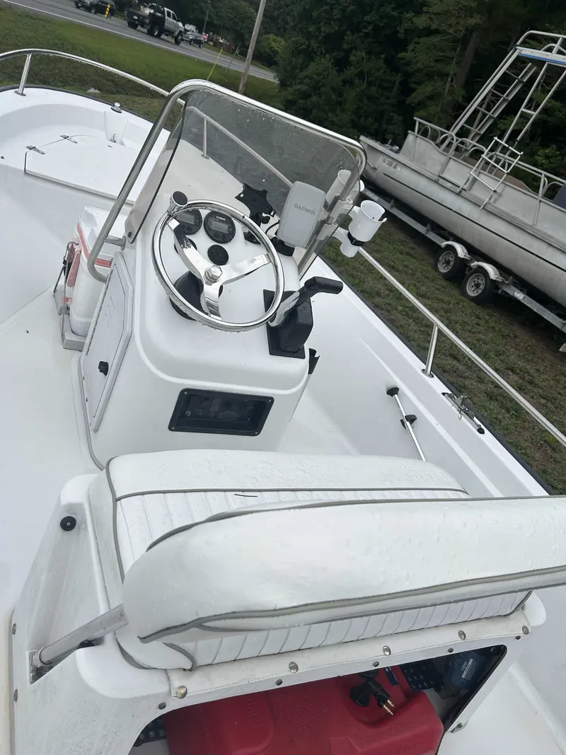 Slide: The Image of A white boat with a helm and bench seat, parked on a trailer on land. - 2