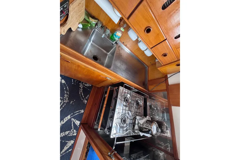 Slide: The Image of 1985 Transpacific Marine Pacific Eagle 32 yacht kitchen with stove, sink, and wooden cabinetry. - 37