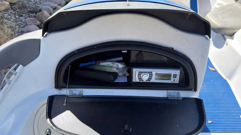 Slide: The Image of An open storage compartment on a Sea-Doo Challenger 2000 reveals a radio and other items. - 12