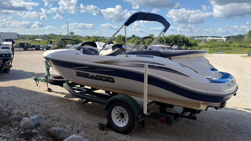Slide: The Image of A white and blue 2002 Sea-Doo Challenger 2000 boat on a trailer in a gravel lot. - 4