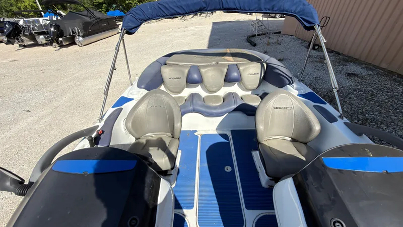 Slide: The Image of A 2002 Sea-Doo Challenger 2000 with blue and gray seats, parked on a gravel lot. - 20