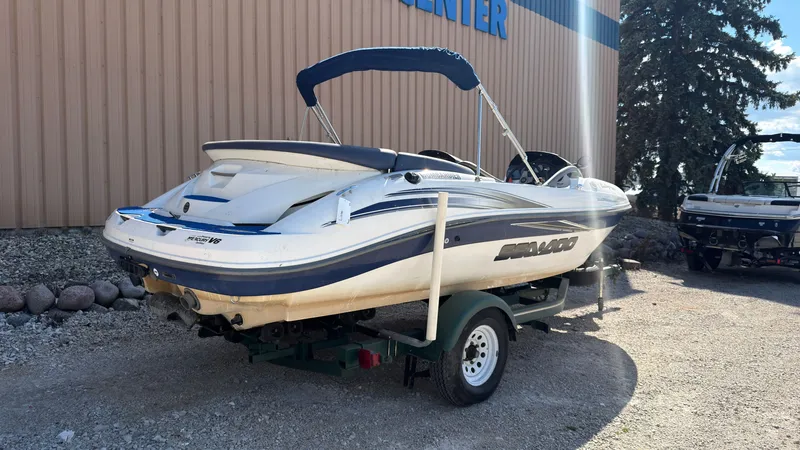 Slide: The Image of A white 2002 Sea-Doo Challenger 2000 boat on a trailer in front of a building. - 2