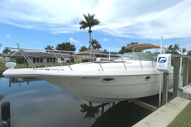 The Image of 2000 Monterey 330 Sport Yacht docked by a waterfront home under a partly cloudy sky. - 0