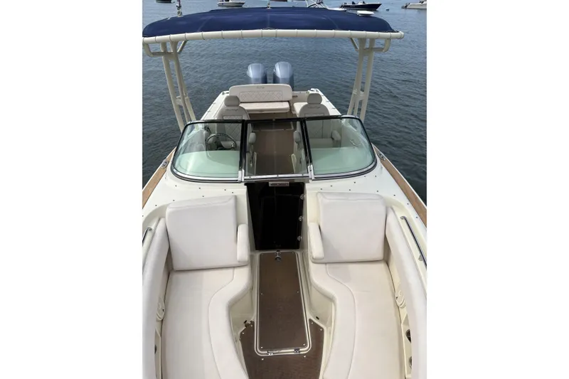 Slide: The Image of 2017 Chris-Craft Calypso 26 boat interior with seating and canopy on water. - 6