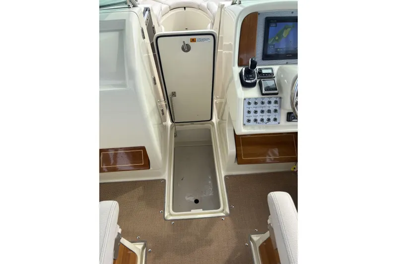 Slide: The Image of 2017 Chris-Craft Calypso 26 boat interior with control panel and storage compartment. - 19