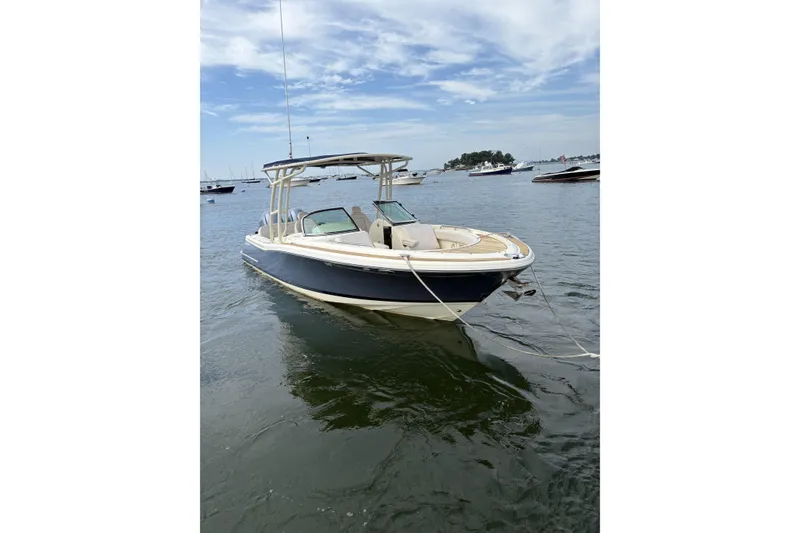 Slide: The Image of 2017 Chris-Craft Calypso 26 boat anchored on calm water under a partly cloudy sky. - 1