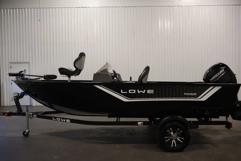 Slide: The Image of 2027 Lowe Fishing Machine 1625SC boat on trailer, side view in indoor setting. - 24