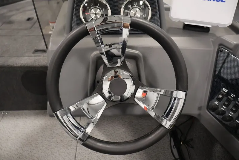 Slide: The Image of Steering wheel of 2027 Lowe Fishing Machine 1625SC boat, featuring chrome accents and dashboard controls. - 16