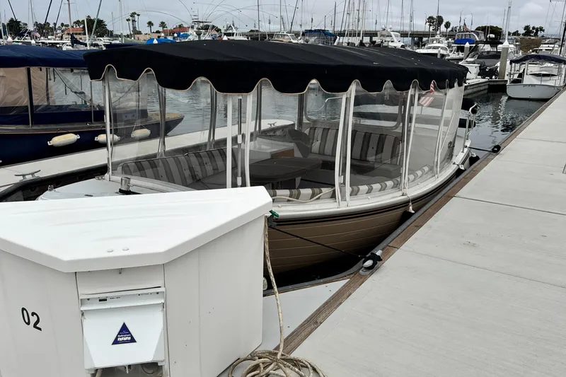 Slide: The Image of 2023 Duffy Bay Cruiser docked at marina with striped seating and canopy. - 7