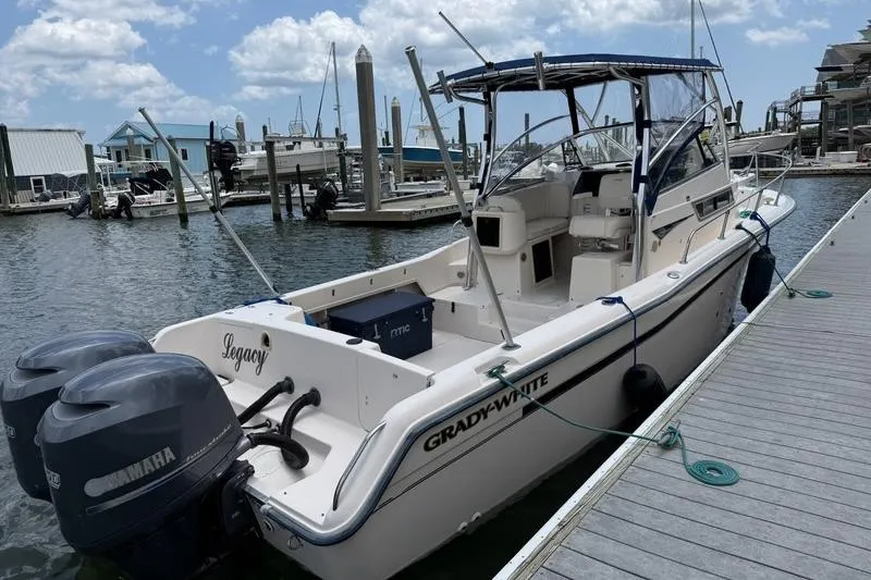 The Image of 1999 Grady-White Islander 268 boat docked, featuring twin Yamaha engines, under a partly cloudy sky. - 1