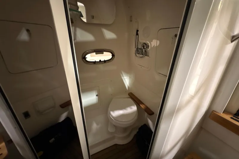 Slide: The Image of Interior of 2026 Boston Whaler 380 Outrage boat bathroom with compact design and porthole window. - 23