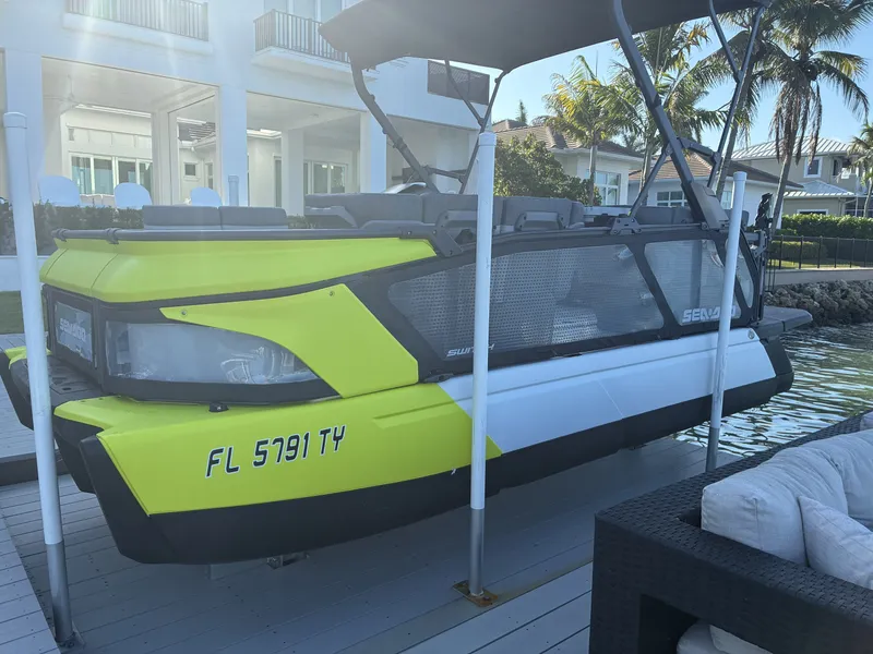 Slide: The Image of A Sea-Doo Switch pontoon boat is lifted on a dock, with a modern house in the background. - 13