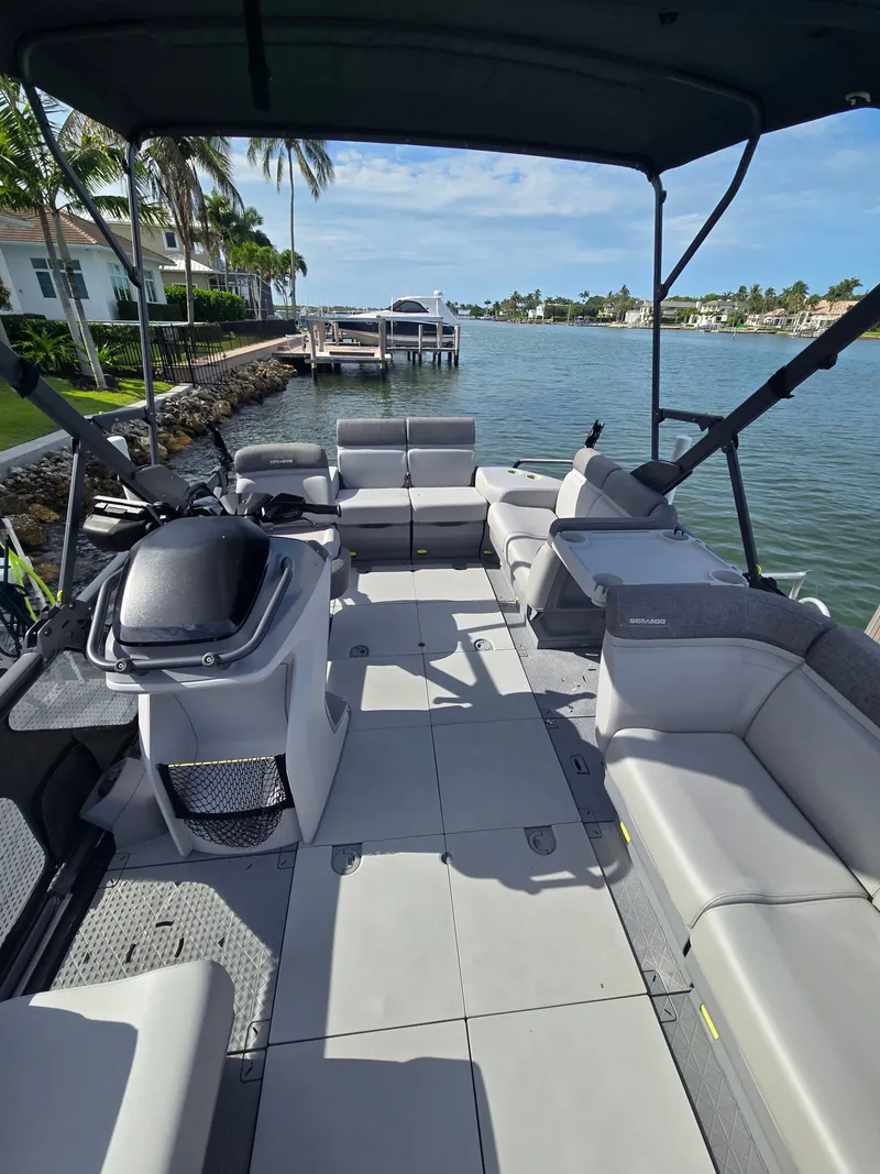 Slide: The Image of A modern pontoon boat with gray seating and a helm, situated in a calm canal. - 7