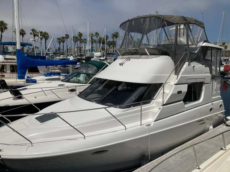 The Image of A 1999 Silverton 322 Motor Yacht docked in a marina, surrounded by other boats. - 0