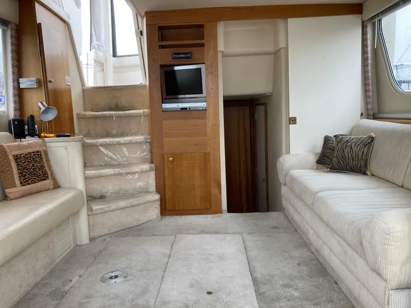 Slide: The Image of Interior of a 1999 Silverton 322 Motor Yacht with beige sofas and a small TV. - 14