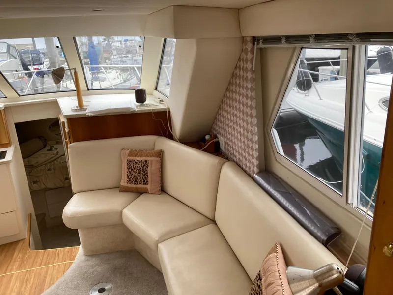 Slide: The Image of Interior of a 1999 Silverton 322 Motor Yacht with cream sofa and windows. - 16