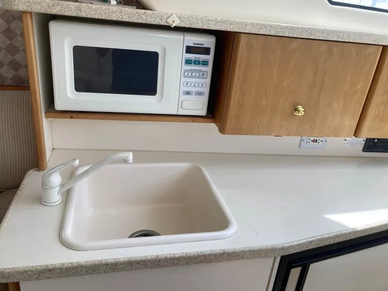 Slide: The Image of A kitchenette with a sink, microwave, and cabinets on a yacht. - 24