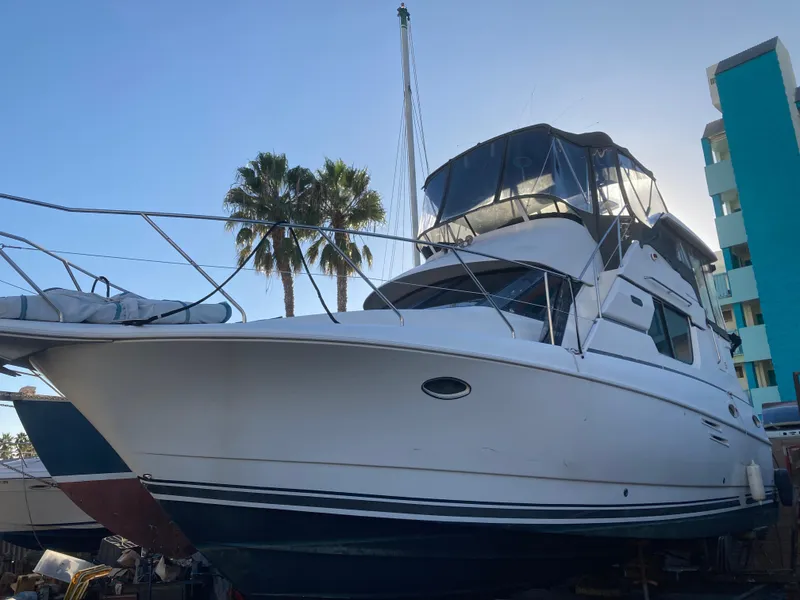 Slide: The Image of A 1999 Silverton 322 Motor Yacht is on land, surrounded by palm trees and buildings. - 5