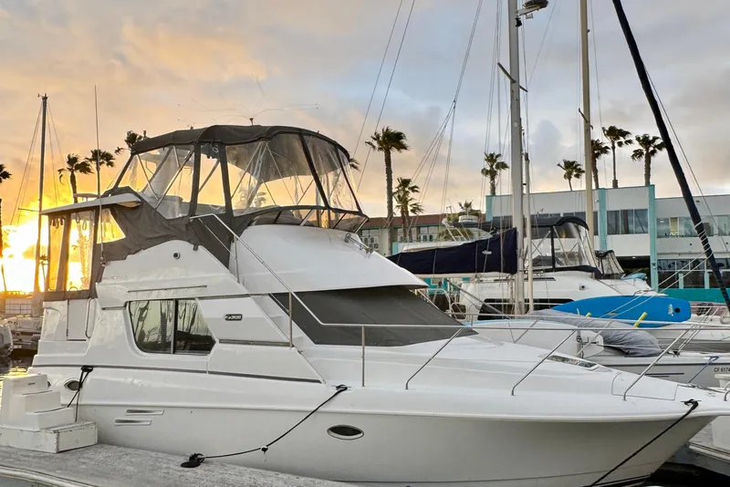 The Image of 1999 Silverton 322 Motor Yacht docked at sunset with palm trees in background. - 0
