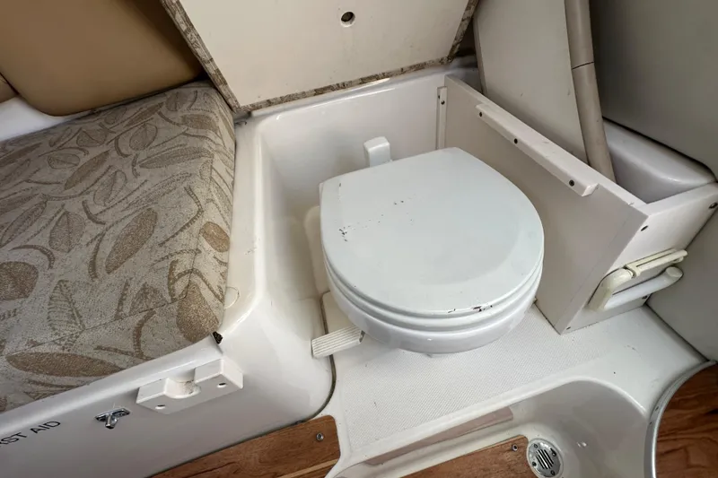 Slide: The Image of 2006 Robalo R245 Walkaround boat interior with compact toilet and cushioned seating. - 14