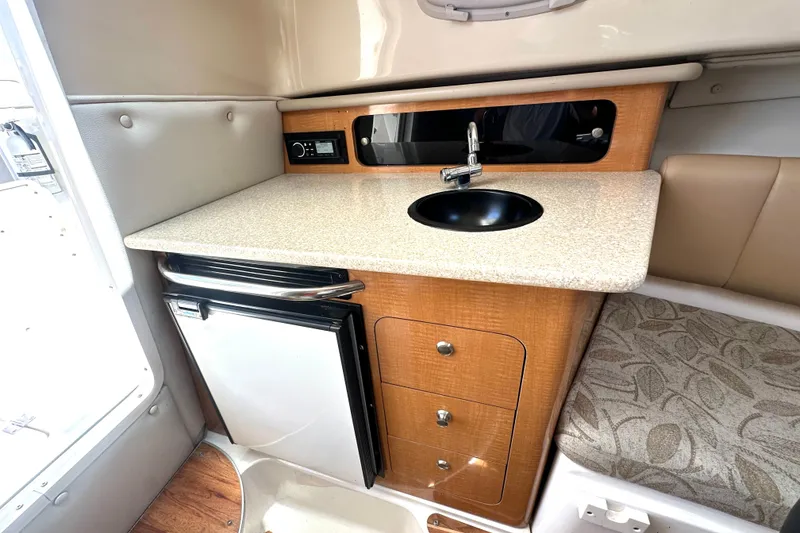 Slide: The Image of 2006 Robalo R245 Walkaround cabin interior with kitchenette, sink, and mini fridge. - 15