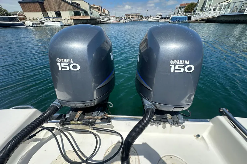 Slide: The Image of Twin Yamaha 150 engines on a 2006 Robalo R245 Walkaround boat in a marina. - 19