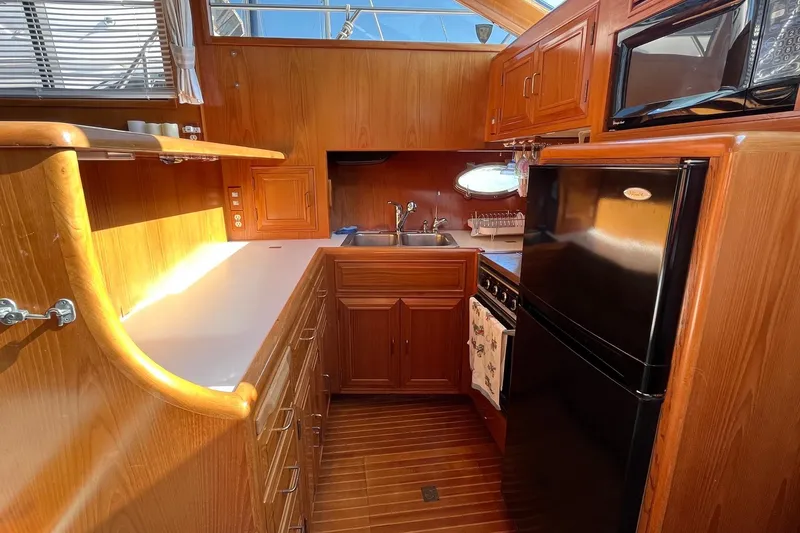 Slide: The Image of 1989 Ocean Alexander 440 Sundeck CPMY kitchen with wood cabinetry, black appliances, and ample counter space. - 10