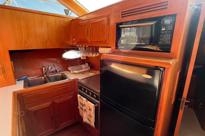 Slide: The Image of 1989 Ocean Alexander 440 Sundeck CPMY galley with wood cabinetry, microwave, and refrigerator. - 9