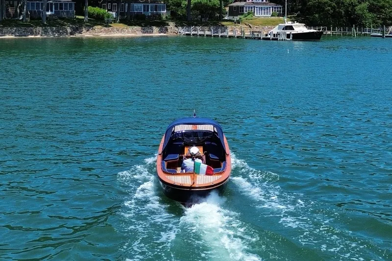 Slide: The Image of A 2003 Castine Harbor Launch boat cruising on a serene lake near waterfront homes. - 4