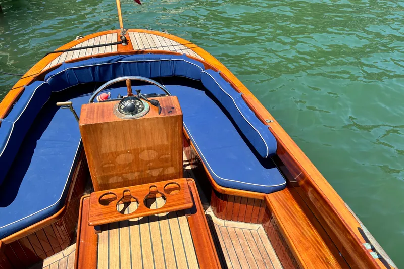 Slide: The Image of 2003 Castine Harbor Launch boat with wooden deck and blue cushions on water. - 10